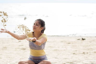 Young woman on beach against sky