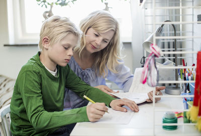 Mother helping son with homework at table