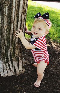 Portrait of cute boy standing on tree trunk