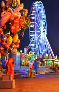 Illuminated ferris wheel in amusement park at night