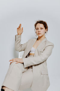 Portrait of teenager girl sitting against white background