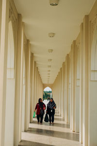 Rear view of people walking in corridor of building