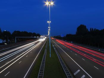 Light trails on road against sky at night