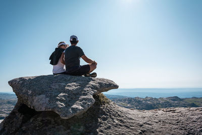 Full length of man on rock by sea against clear sky