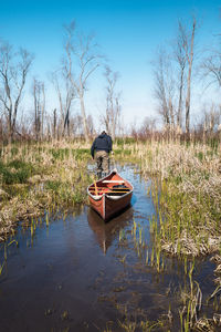 Man sitting on lake against sky