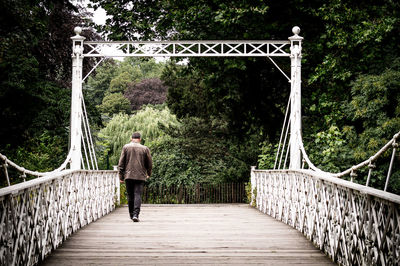 Rear view of man walking on footbridge