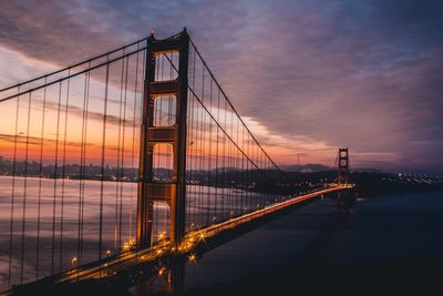 Golden gate bridge over river against cloudy sky during sunset