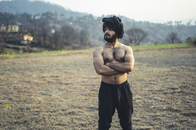 Young indian farmer with a turban standing on a barren field. crops not growing due to shortage