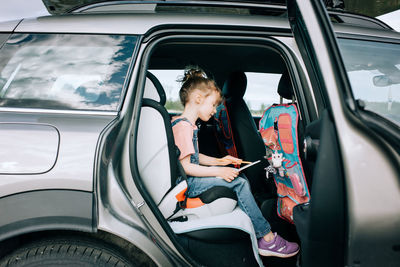 Girl sitting in the car drawing pictures feeling happy