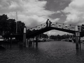 Bridge over river against cloudy sky