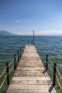 Wooden pier over sea against blue sky