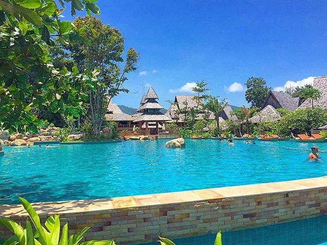 water, blue, tree, building exterior, built structure, clear sky, architecture, lake, nautical vessel, nature, day, swimming pool, tranquility, turquoise colored, sunlight, growth, boat, outdoors, beauty in nature, green color