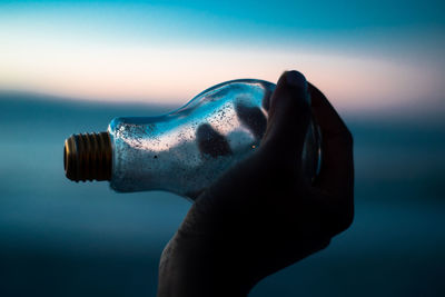 Close-up of hand holding water against blue background