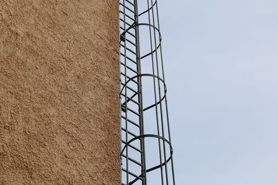 Low angle view of metal ladder against sky