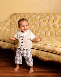 Full length of baby boy standing by sofa at home