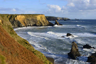 Scenic view of sea by cliff against sky