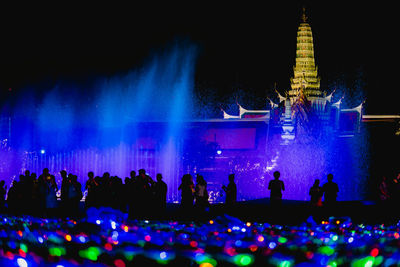 Group of people watching firework display at night