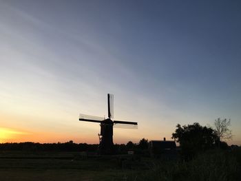 Silhouette cross on field against sky during sunset