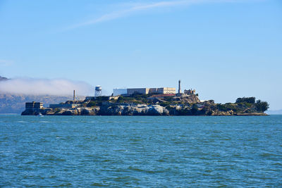 View of sea and buildings against blue sky