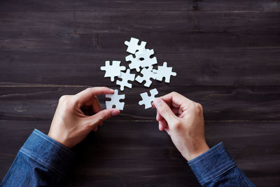 Cropped image of hands holding jigsaw puzzle