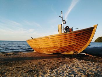 Boat moored on beach against sky