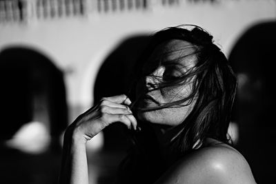 Sunlight falling on young woman with tousled hair against building