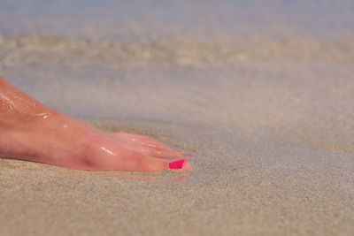 Midsection of woman on sand at beach