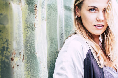 Portrait of smiling young woman standing against window