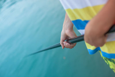 Midsection of man fishing in lake