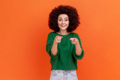 Portrait of young woman standing against colored background