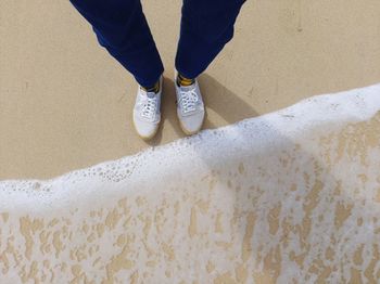 Low section of man standing on sand