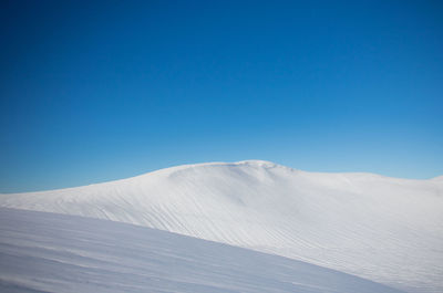 Scenic view of snowcapped mountains against clear blue sky