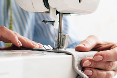 Close-up of craftswoman sewing textile on machine at workshop