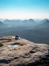 Sweaty running shoes on the edge of a rock. the top of the mountain above a long valley.