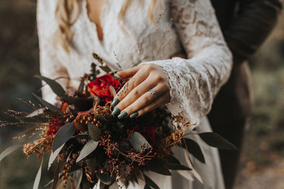 Midsection of woman holding red flowering plant