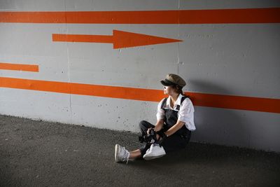 Full length of woman sitting against wall