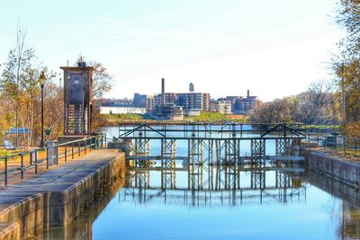 Footbridge over lake in city against sky