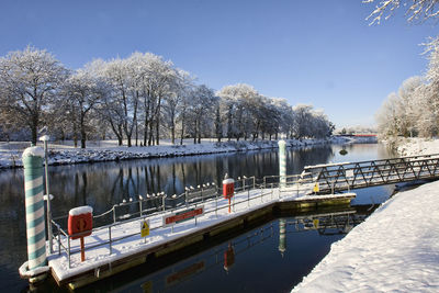 Scenic view of river amidst trees on snowcapped field during winter