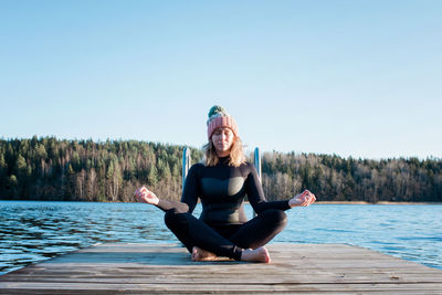 Woman meditating in a wetsuit at the beach before cold water swimming
