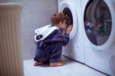 Rear view of boy standing on tiled floor