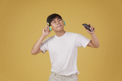 Full length of boy holding yellow while standing against orange background