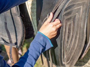 An unrecognizable girl setting horse saddle at horse stable. setting pad and strips of stirrups