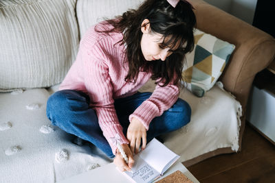 High angle view of woman reading book at home