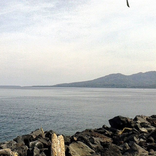 water, sea, tranquil scene, tranquility, scenics, sky, rock - object, beauty in nature, mountain, nature, shore, idyllic, horizon over water, stone - object, rock, beach, cloud - sky, outdoors, non-urban scene, calm