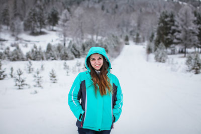 Portrait of smiling woman wearing warm clothing standing in snow