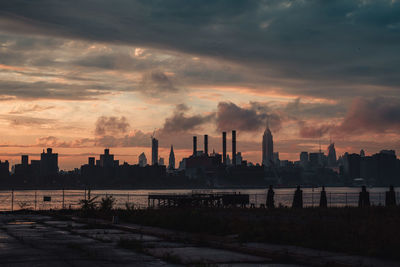 Cityscape and river against sky during sunset