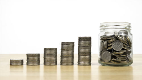 Stack of coins in jar against white background