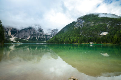 Scenic view of lake by mountains against cloudy sky