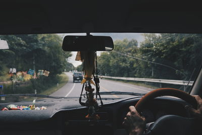 Cropped hands of man driving car on road