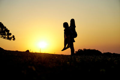 Silhouette people standing on field against sky during sunset